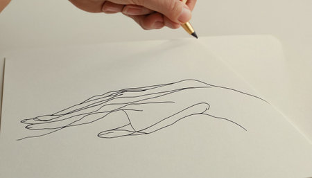 Hand drawing a hand with a pen on a white sheet of paperの素材