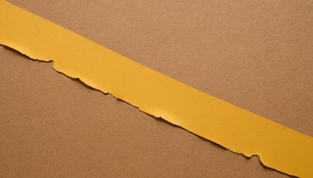 Torn yellow paper with space for your message on brown background.の素材