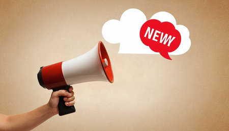 Close up of human hand holding megaphone with new news speech bubbleの素材