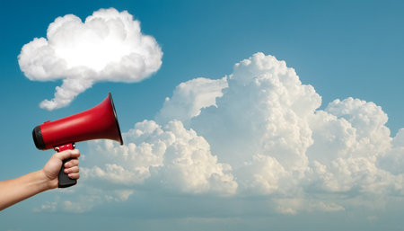 Close up of human hand holding megaphone with cloud in the skyの素材