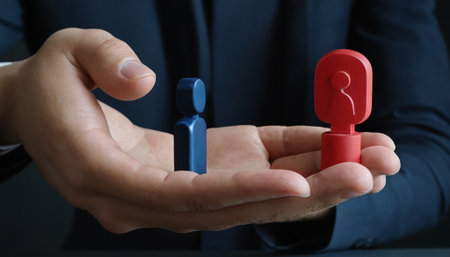 Businessman hand holding red and blue people figures on dark background, closeupの素材