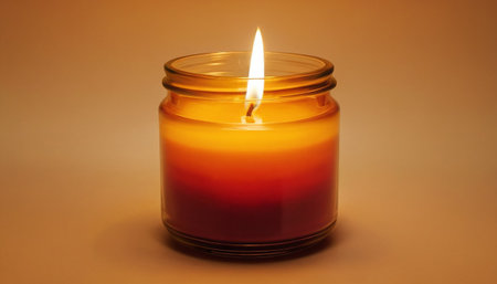 Candle in a glass jar on a brown background, close-upの素材