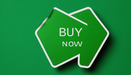 Buy now sign on green paper background. Top view. Copy space.の素材