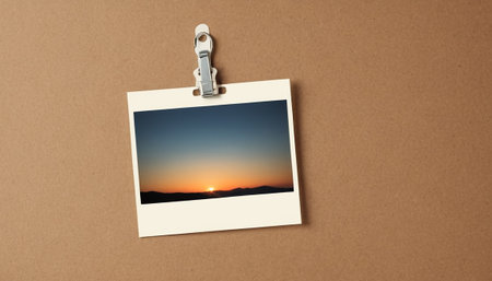 Blank photo frame hanging on clothespin with sunset sky in backgroundの素材