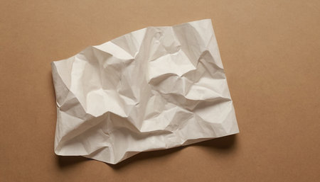 Crumpled white paper on brown background. Top view. Copy space.の素材