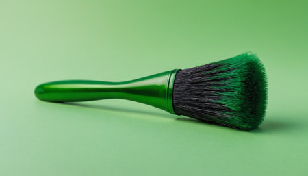 Green paint brush on a green background. Horizontal studio shot.の素材