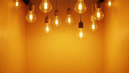 Vintage incandescent Edison light bulbs hanging on yellow wall.の素材