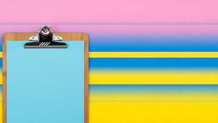 A clipboard with blue paper rests on a vibrant background of horizontal pink, blue, and yellow stripes.の素材
