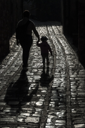 adult and child holding hands in backlightの写真素材