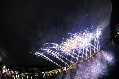 Fireworks on the Lugano Lake in a summer evening seen from lakefornt of Lavena-Ponte Tresa, Lombardy - Italyの写真素材