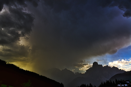 Storm clouds and downpour on the mountains of Alta Badia in summer sunset, Corvara in Badia -...