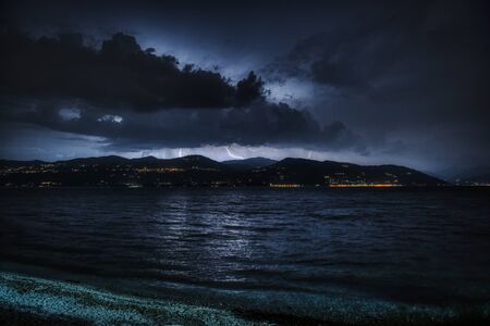 Thunderstorm over the mountains of Piedmont and Major Lake in foreground in the end of summerの写真素材