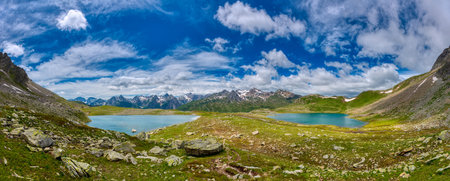 Two lakes in the Italian alps in summer season with clouds in the blue skyの写真素材