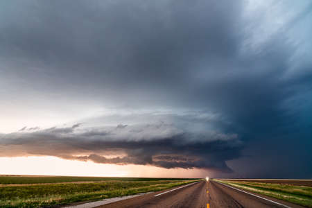 Supercell thunderstorm over a road at sunset.