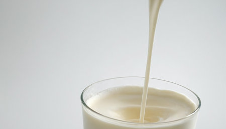 Milk pouring into a glass on a white background, close-upの素材