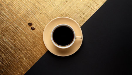 Cup of coffee on black and gold background. Top view.の素材