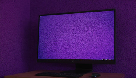 Computer monitor with blank screen on the table in front of purple wallの素材