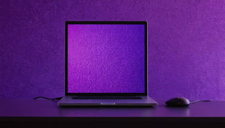 Laptop computer with blank screen and mouse on purple wall background.の素材