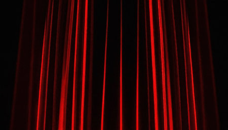 Red stage curtain isolated on a black background. Red curtain with red light.の素材