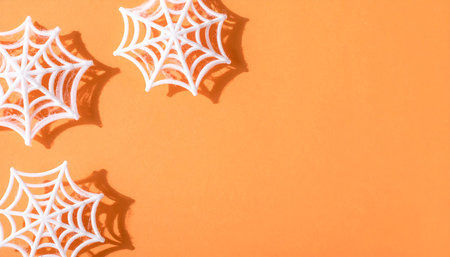 White spider web on orange background. Halloween concept. Flat lay, top view.の素材