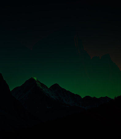 Mountain landscape at night with green light and snow-capped peaksの素材