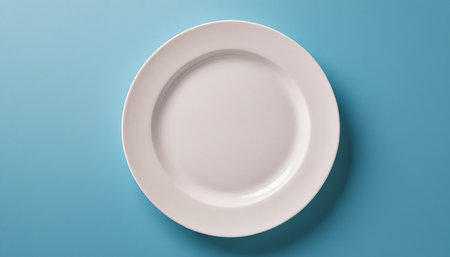 Empty white plate on blue background. Flat lay, top view.の素材
