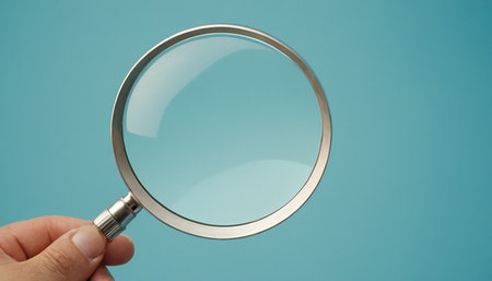 Magnifying glass in hand on blue background. Close-up.の素材