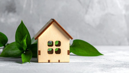 Wooden toy house with green leaves on light background, closeupの素材