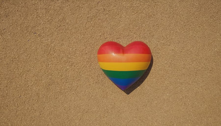 Heart shaped LGBT flag on a beach sand background. Copy space.の素材