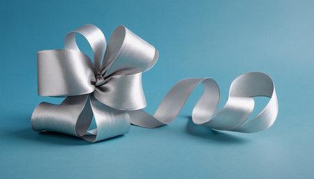 Silver ribbon bow on blue background with copy space for your text.の素材
