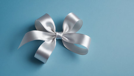 Silver ribbon bow on blue background. Flat lay, top view.の素材