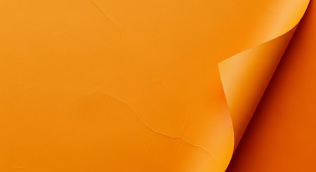 A close-up view of a vibrant orange paper sheet with one corner dramatically curled upwards. This action reveals a slightly darker shade of orange beneath the surface, creating a subtle gradient and a sense of depth. The lighting emphasizes the smooth texture of the paper and the sharp shadow cast by the curled edge. is backgrounds orの素材