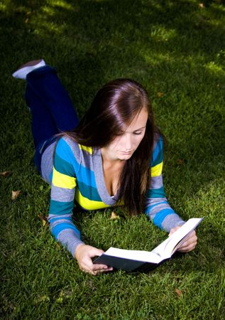 Close up on a Beautiful Girl Laying Down in the Park Reading a Bookの写真素材