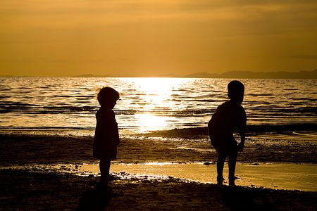 Kids playing on the beach - silhouette shotの写真素材