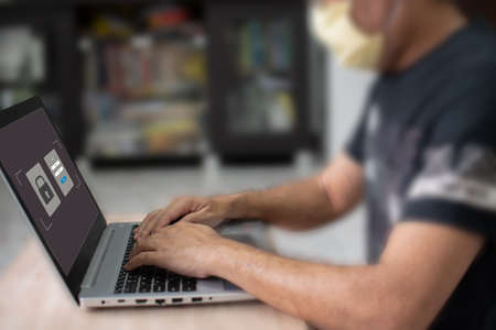 Work at home with computer and internet Laptop screen showing the login for online shopping. A man typing a keyboard key to use a computer network A laptop on a wooden table in a blurred backgroundの写真素材