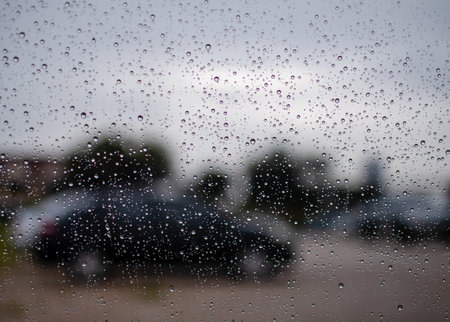 Bright raindrops on car glass, evening after work, in the parking, take close-up an image, black-gray background, blur, landscape, and beautiful image.の写真素材