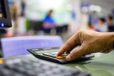 Close-up a man's finger pressing a calculator on a glass table in an office To calculate bank...