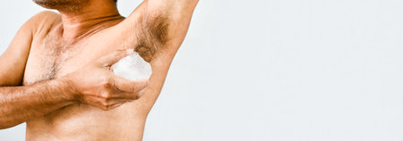 Close-up a men apply alum to their armpits to eliminate body odor after they finish showering. The male hand holds alum and rubs the armpit area to eliminate the bad smell. Copy space on design, textの写真素材