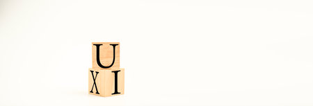 A wooden cube on a white table with text UI, UX. Concept of development and design and development,...