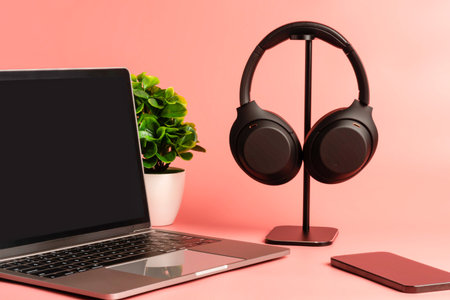 Black headphones hang on a table. Concept of playing music with a smartphone and listening with wireless headphones in the living room and Work at home. studio. Selective focus. pink background.の写真素材