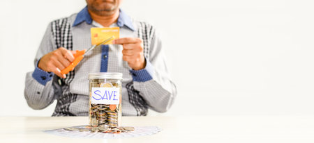 Coins and text SAVE in a glass jar placed on a wooden table. Concept of saving money for investment in the future and not superfluous, business, banking, finance, credit card, blurred backgroundの写真素材