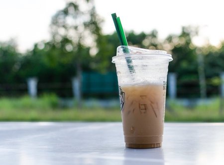 Iced coffee in plastic cup on table with nature background, stock photoの写真素材