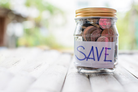 Coins and text SAVE in a glass jar placed on a wooden table. Concept of saving money for investment...