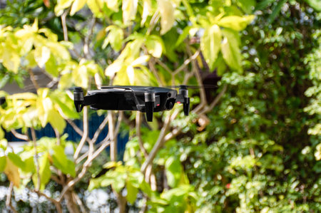 nobody, modern black drone flying in nature with 4 propellers, 4k camera photo, and video. The concept for professionals in the unmanned aircraft technology industry. Close up, crop, Blur background.の写真素材