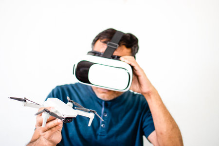An alone man holds a drone and plays VR to operate the drone. The young man was happy while watching...