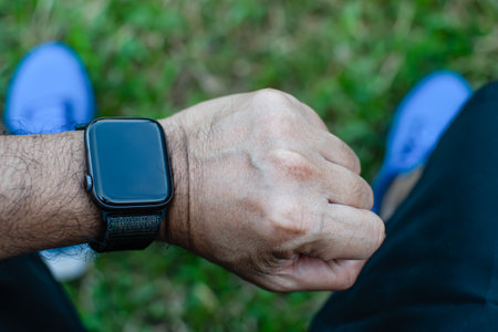 The man was tired and sat down to relax, looking at the smart watch after jogging. It's a close-up...