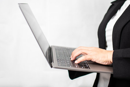 A businesswoman in a suit is using a laptop to work and typing at a keyboard. Concept for Marketing, Finance, Banking, Equity, Stock Trading. woman hold notebook computer Close Up, blurred backgroundの写真素材