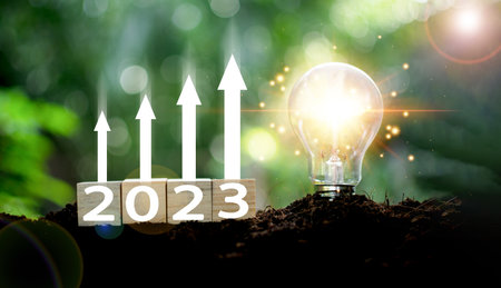 The new year 2023 and bright light bulb on the mound. Concept of a startup that drives the economy,...