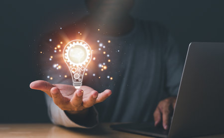 Inspiration of ideas for sustainable business development. Hand of a man holding illuminated light bulb, concept creativity with bulbs that shine glitter. an Idea of innovation and inspiration conceptの写真素材