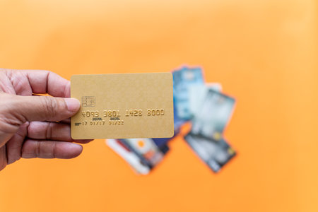 Businessman showing debit card online shopping, payment, online banking, money transfer, concept, selective focus, copy space, right. Closeup, man's hand holding credit card on orange, blur backgroundの写真素材